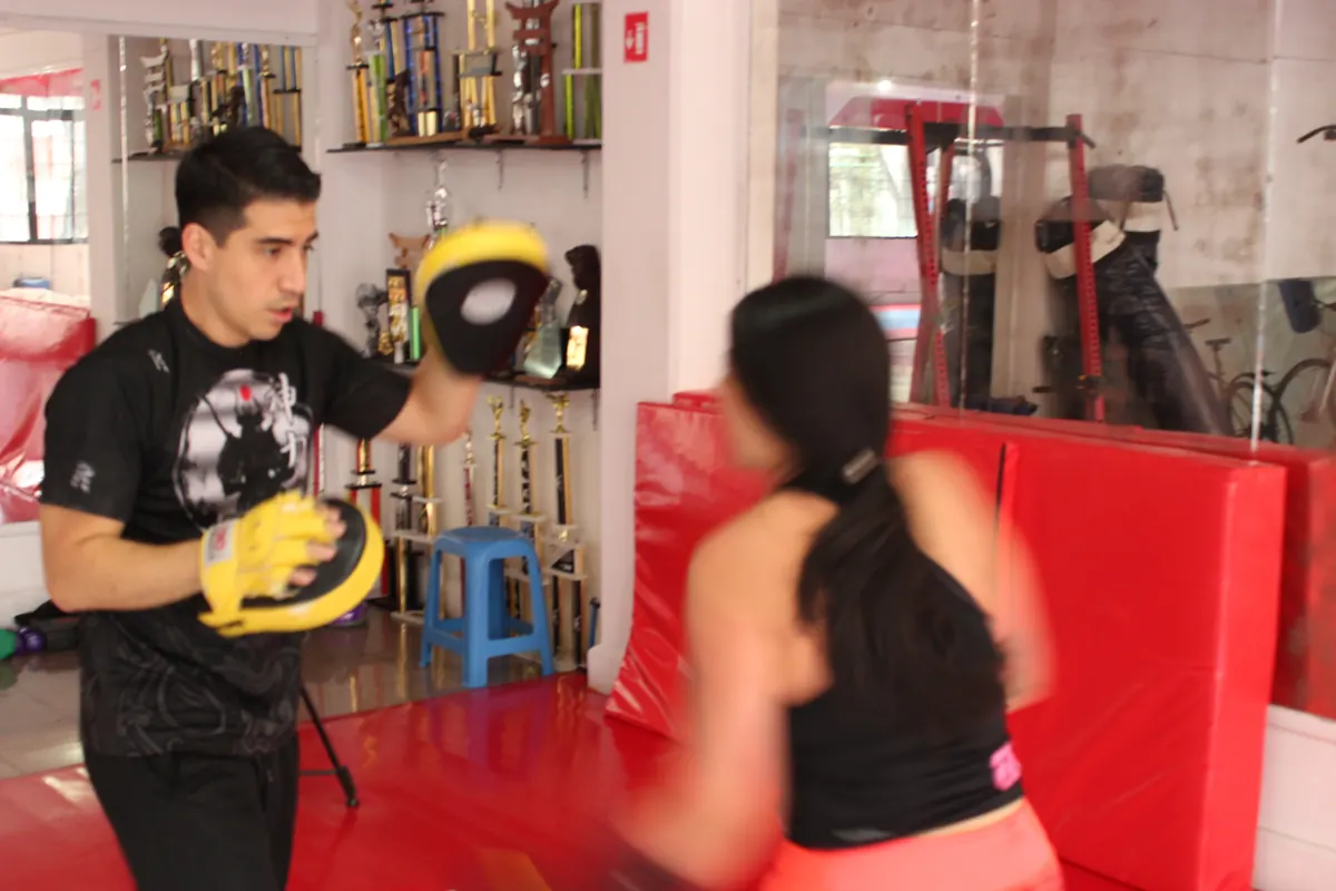 Alumna golpeando manoplas con su entrenador en Fitness Training